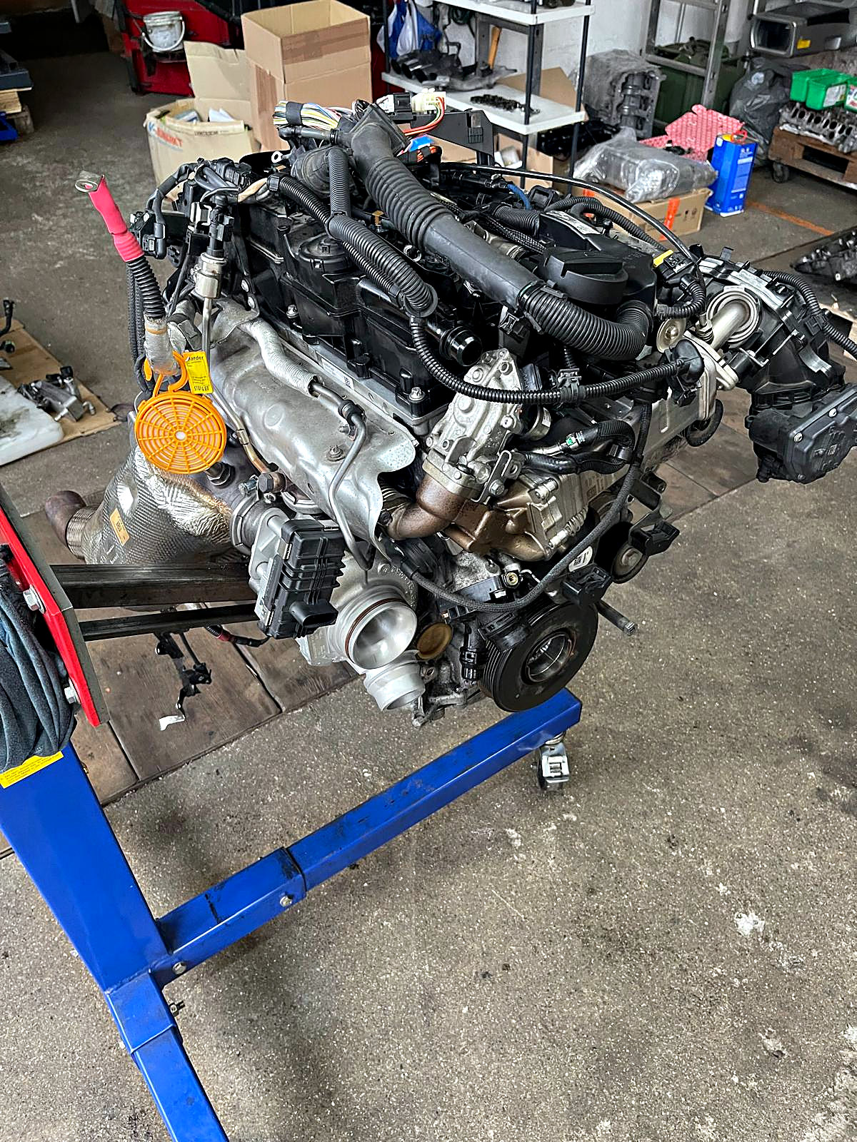 Kompletter BMW-Motor mit Anbauteilen auf dem Montagebock in der Halle