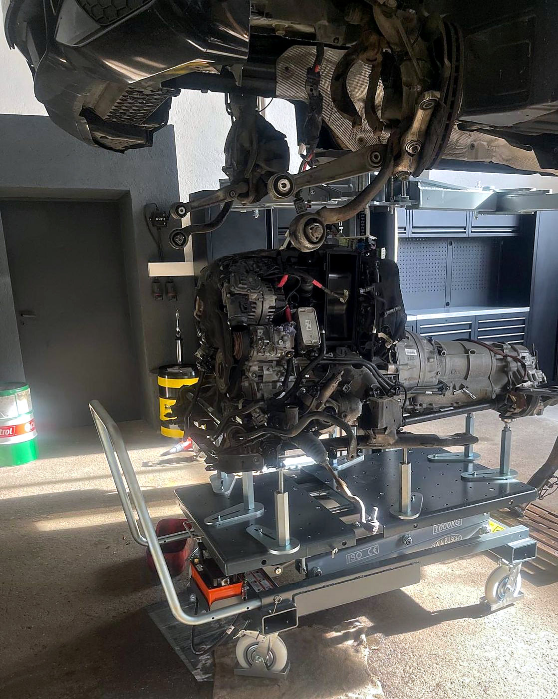 BMW X5 auf der Hebebühne, Motor und Getriebe auf dem Getriebeheber unter dem Fahrzeug