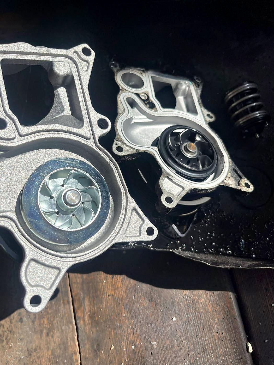 Zwei Wasserpumpen nebeneinander: links die neue mit Metallflügelrad, rechts die ausgebaute